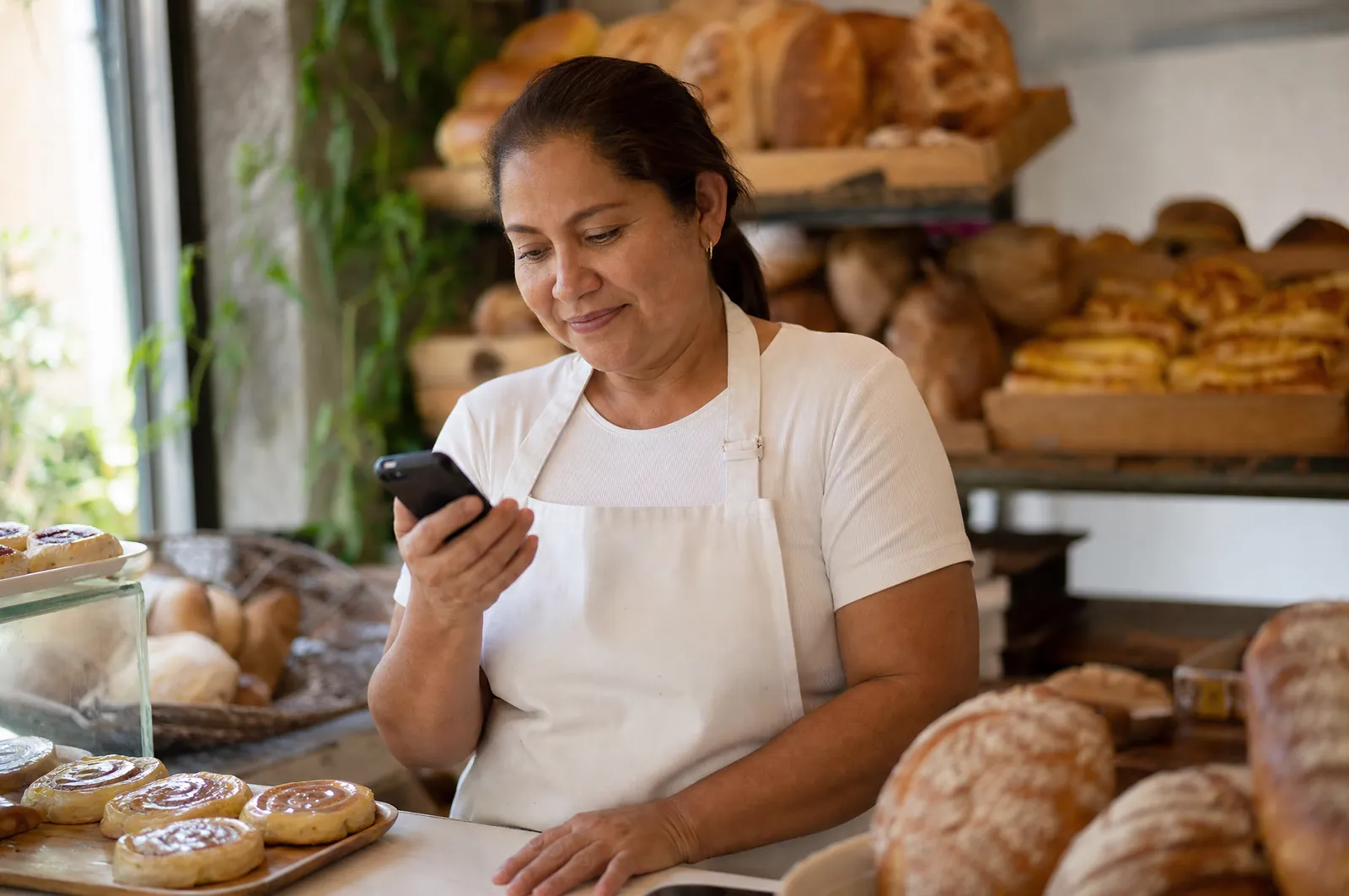 Comerciante venezolana en su panadería revisando un cobro en KobroPay
